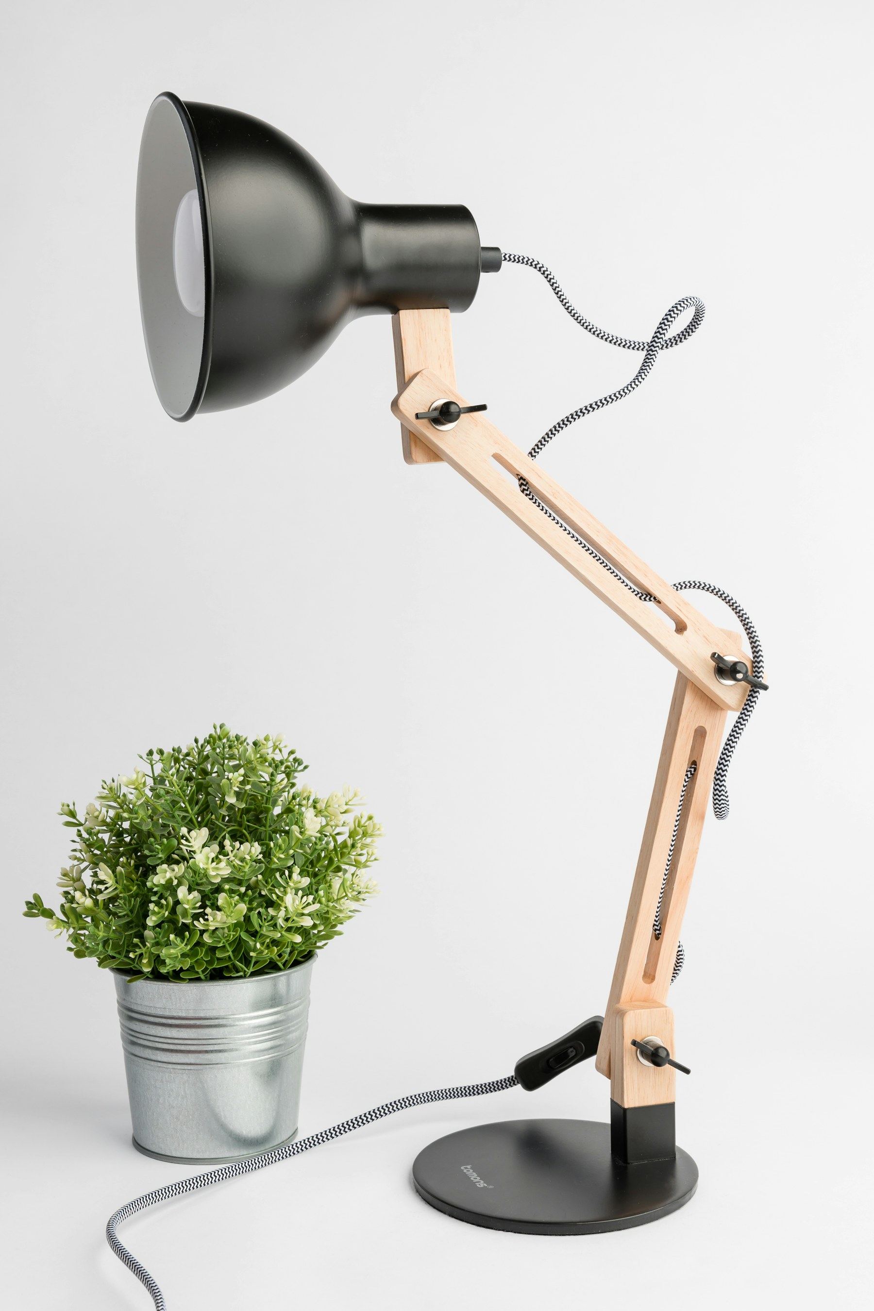 Black and white cantilever desk lamp beside a plant